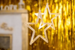 Christmas gold garland on blurred festive background. Happy New Year's card.Christmas season, glass lanterns, star hanging in living room as decoration.