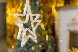 Christmas gold garland on blurred festive background. Happy New Year's card.Christmas season, glass lanterns, star hanging in living room as decoration.