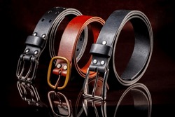 A group of multi-colored leather belts on a black background.