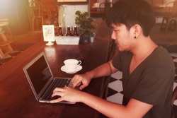 young Asian man relax and working  in coffee shop with soft light and soft focus tone