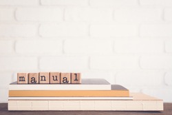 The word Manual, text on wooden cubes on top of books. Background copy space, vintage minimal style. Concepts of help information, Instructions or user guide for education and business products.