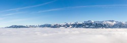 Fantastic panoramic view of snow mountain range stick out of inversion fog layer. Great panorama with sunny blue sky above the clouds. Ofterschwanger Horn, Alps, Allgau, Bavaria, Germany.