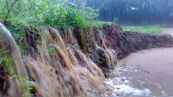 Mud and flowing water reach a pond / swamp during heavy rain looks like water fall causing soil erosion with wave and splash