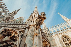 Roof of Milan Cathedral Duomo di Milano with Gothic spires and white marble statues. Top tourist attraction on piazza in Milan, Lombardia, Italy. Wide angle view of old Gothic architecture and art