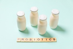 Small bottles with probiotics and prebiotics dairy drink on blue background. Production with biologically active additives. Fermentation and diet healthy food. Bio yogurt with useful microorganisms.