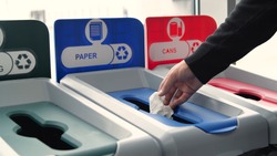 Close-up of man throwing garbage into sorting bins. Media. Man throws garbage into colored bins for sorting. Sorting garbage helps in recycling and supports ecology of nature