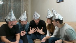 Group of people with foil on their heads discussing conspiracy theories. Friends with foil on their heads. You know, so they can't read your mind