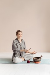 Girl and Tibetan bowls, Palo Santo, essential oils. A young woman sits on the floor and meditates.