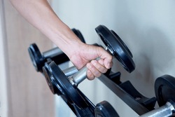 Dumbbells are in the hands that are raised in the gym.            