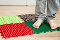 Toddler baby foot massage mat. Exercises for legs orthopedic massage carpet. Flat feet prevention and Orthopedic massage puzzle floor mats for children development and healthy growth.