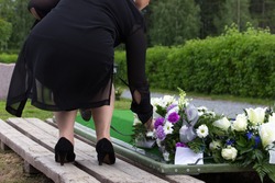 Woman laying flowers on a grave at a funeral