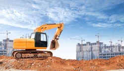 An articulated wheel crawler loader or dozer on mound with the industrial building construction site and blue sky background concept