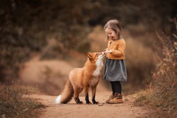 a little girl with a Fox in autumn forest