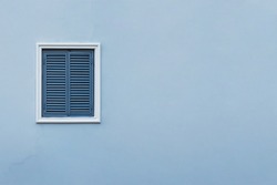 Blue wall of the house with a closed window left and details.
