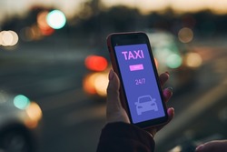 Woman ordering taxi online using mobile app on smart phone. Booking taxi using application online. Arranging taxi ride in downtown city street. Car sharing. Taxi service on mobile. City traffic lights