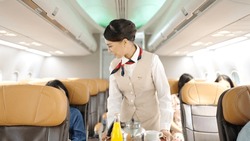 Asian female flight attendant serving food and drink to passengers on airplane. Airline service