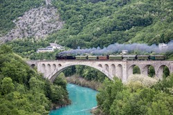Old steam train on the Solkan bridge near Nova Gorica, Slovenia, Europe. Lots of black and gray steam hiding the locomotive, full frame.