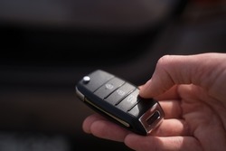 Person opens the trunk of the car with a remote access key. Close-up. Travel by car, logistics