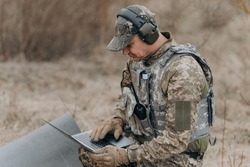 A soldier works on his laptop.