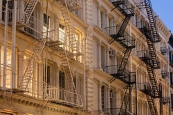 Facades of Soho loft buildings with fire escapes at dusk. Lower Manhattan, New York City