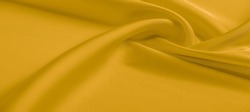 Yellow silk fabric. A very lightweight viscose fabric with rich drapery and a smooth texture with a subtle matte sheen. background texture, pattern.