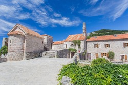 Panoramic view of the historic town of Budva with blooming flowers on a beautiful sunny day with blue sky and clouds in summer,southern Europe. Montenegro, Adriatic Sea. Ancient church of St. Sava 