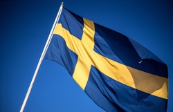 Swedish flag waving In the wind on blue sky Sweden royal flags