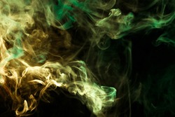Thick colorful smoke of green and yellow on a black isolated background. Background from the smoke of vape