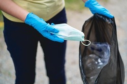 Volunteer charity woman hand holding surgical protective mask during the coronavirus pandemic. Covid-19.  throwing away used protective face mask in garbage discarded mask 