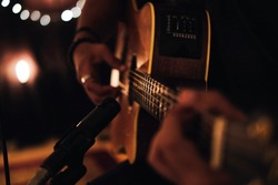 A man playing acoustic guitar in recording session with microphone and beautiful lighting