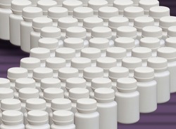 A large quantity of white plastic pill bottles in a production line. An image representing mass production pharmaceuticals, vitamins and  supplements