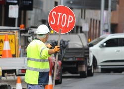 Older man with a stop sign directing traffic in Sydney cbd