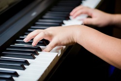 Selective focus to kid fingers and  piano key to play the piano. There are musical instrument for concert or learning music. Close up hand of child musician playing the piano on stage.