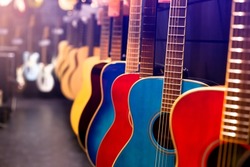 Selective focus too many guitars in musical showroom at musical instrument store. Colorful guitar. Studio shop.