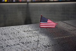 Memorial at Ground Zero Manhattan for September 11 Terrorist Attack with an American Flag Standing near the Names of Victims Engraved