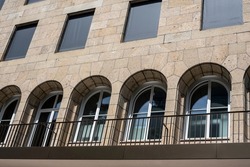 a row of arched windows in a limestone facade of a historic building with metal railing