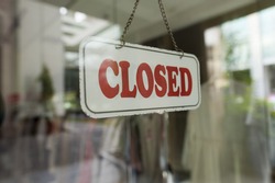 Close up shot of a closed sign hanging up on the glass door. 