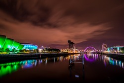 The cityscape of Glasgow city with three landmarks which are The Clyde Arc Bridge, Finnieston Crane and SEC Armadillo Building at the night time.