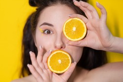 young brunette woman girl with slice of orange fruit near skin face on yellow background. tasty juicy fruit. Tropical fruits, Healthy food. citrus slice. tasty juicy fruit.