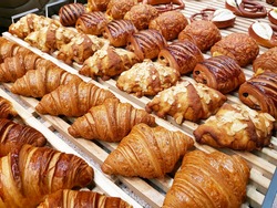 Various croissants rows serving on a shelf in a bakery shop.