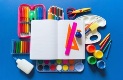 Stationery flat lay. Bright material for a child Back to school. Blue background kid child. Around office supplies are the color of the rainbow.