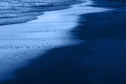 Dusk on the beach of the Mediterranean and mountains range on the horizon. Classic Blue Pantone 2020 year color in nature.