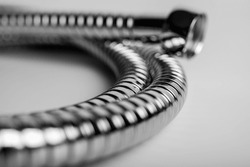 black and white object, close-up, chrome metal shower hose on a light background