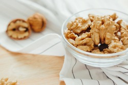 
Peeled walnuts in bowl lie on kitchen table, close-up. Healthy food, source of vegetable protein.