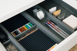 Office supplies in desktop drawer. Writing pens, pencils, paper clips, color sheets for notes. Workplace order. 