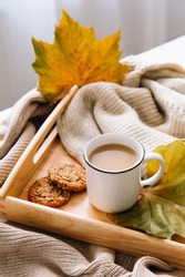 Autumn and winter home still life: a cup of coffee, cookies and yellow leaves. Seasonal breakfast, morning coffee. The concept of home comfort and a relaxed atmosphere.