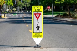 State Law Yield for Pedestrians Within Crosswalk reboundable road sign installed in the middle of the street