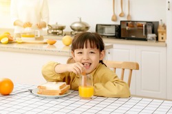 Asian little girl eating bread with juice