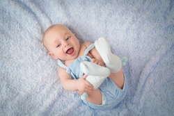 happy and smiling baby in blue clothes on blue color background