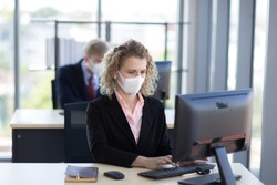Business woman with curly blonde hair wearing a mask sitting in office, Concept,contagious disease, covid 19, coronavirus.